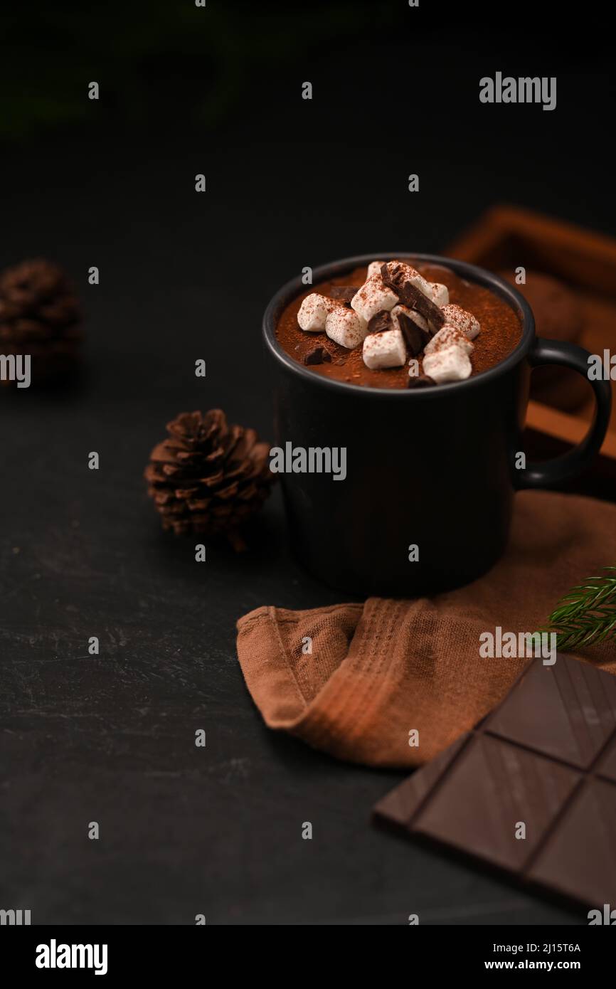 Nahaufnahme, Eine Tasse heiße Schokolade mit Süssigkeiten, brauner Tischdecke und dunklen Schokoriegeln auf schwarzem Hintergrund. Stockfoto