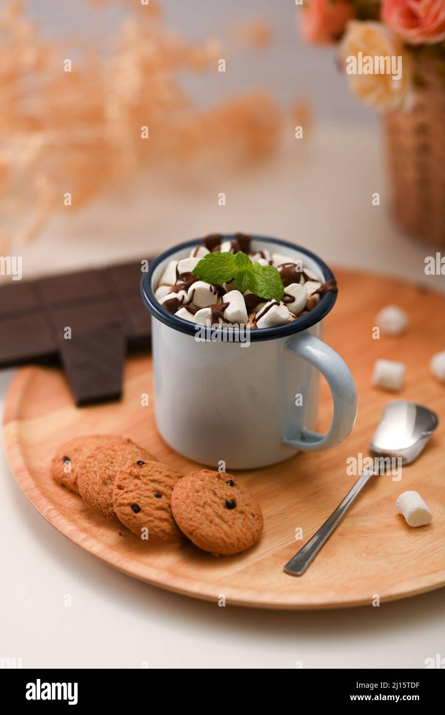 Heiße Minzschokolade mit Marschwalbe, serviert mit Schokoladenkeksen und Schokoladenriegel auf einem Holzteller. Spezielles Urlaubsdrink-Konzept. Stockfoto