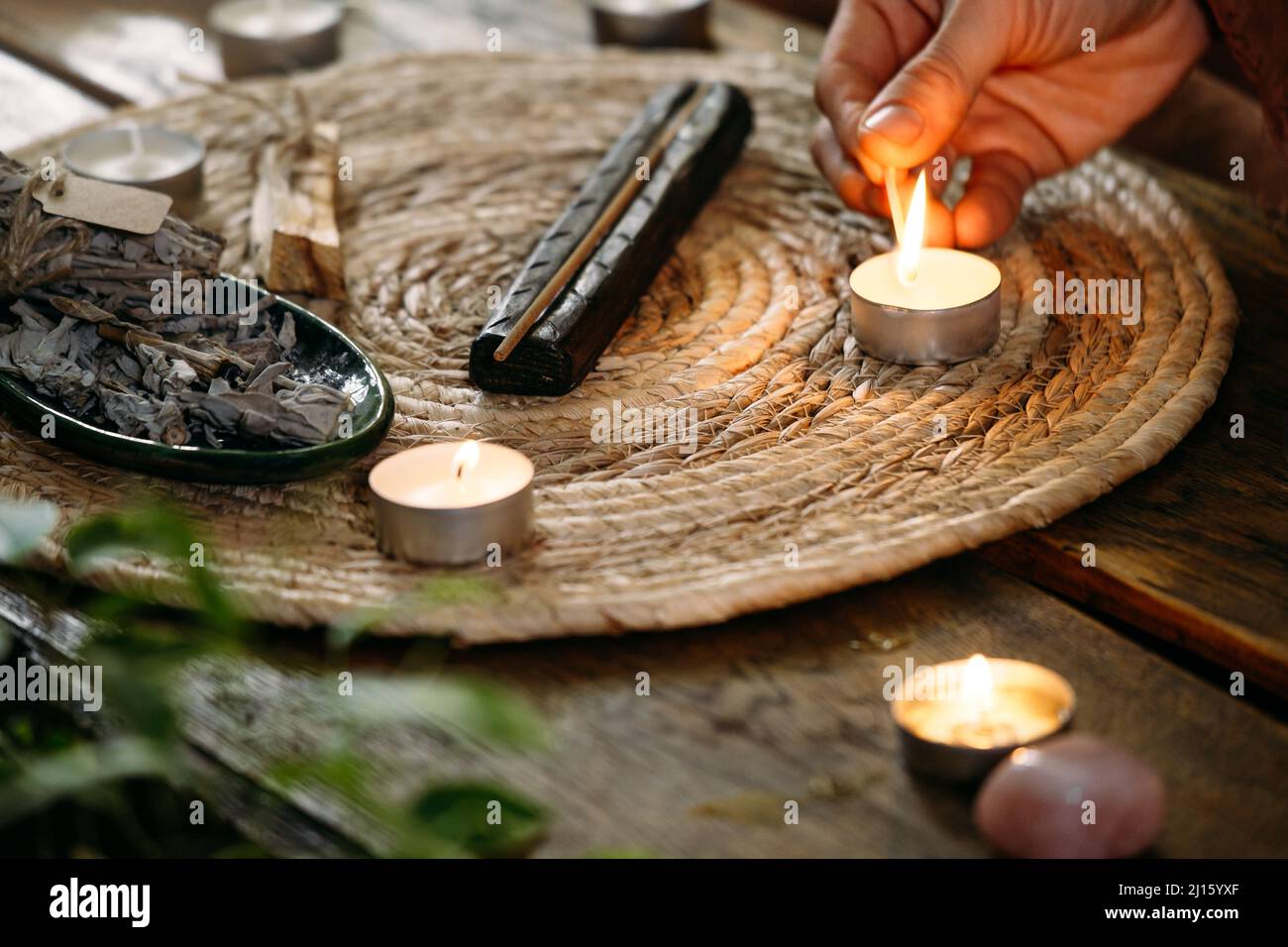 Kerzen auf dem Tisch mit Streichhölzern anzünden. Frauen halten Feuer in der Hand. Gemütliche Dekoration am Abend. Stockfoto