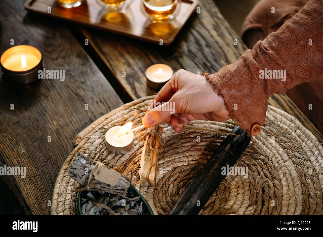 Kerzen auf dem Tisch mit Streichhölzern anzünden. Frauen halten Feuer in der Hand. Gemütliche Dekoration am Abend. Stockfoto