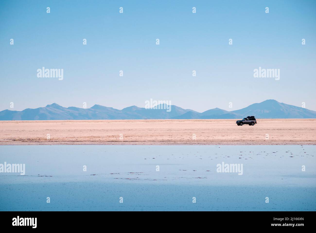 Helle Tageslandschaft des Salar de Uyuni mit Offroad-Auto in Bolivien Stockfoto