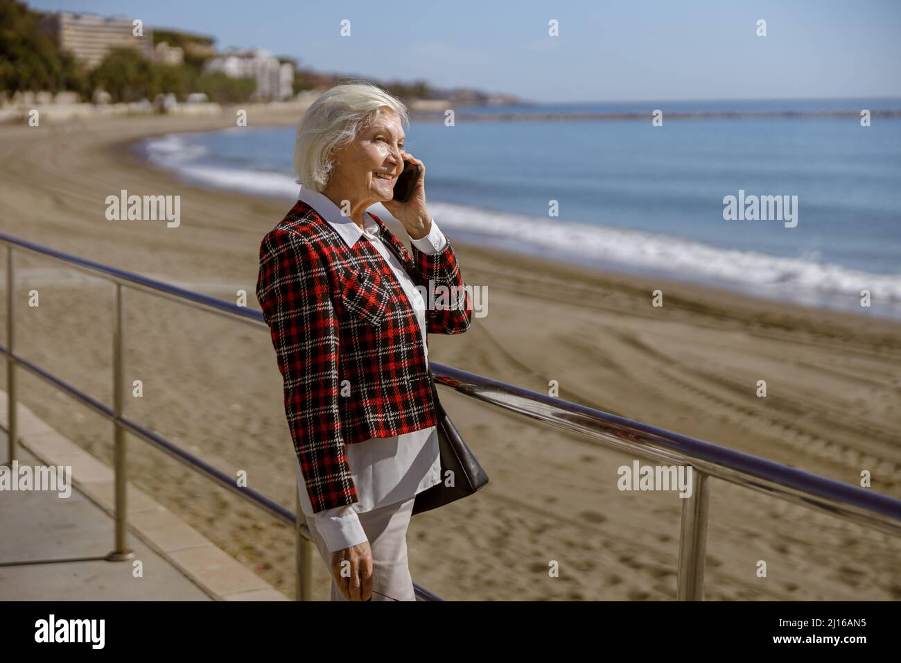 Urbane ältere Dame, die sich im Freien auf dem Meer entspannt Stockfoto