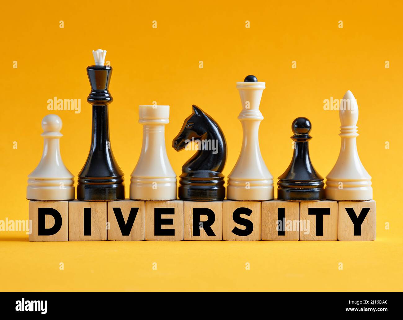 Das Wort Vielfalt auf Holzwürfeln mit verschiedenen Schachfiguren. Diversity-Strategie im Geschäftskonzept. Stockfoto