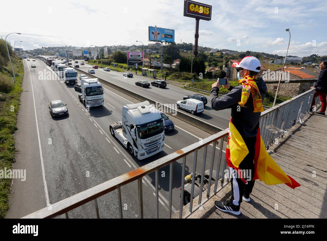 Ein Coruna-Spanien. Person mit dem Schal und der Nationalflagge von Spanien Aufnahme mit dem Handy die Passage des langsamen marsch von Lastwagen protestieren die Stockfoto