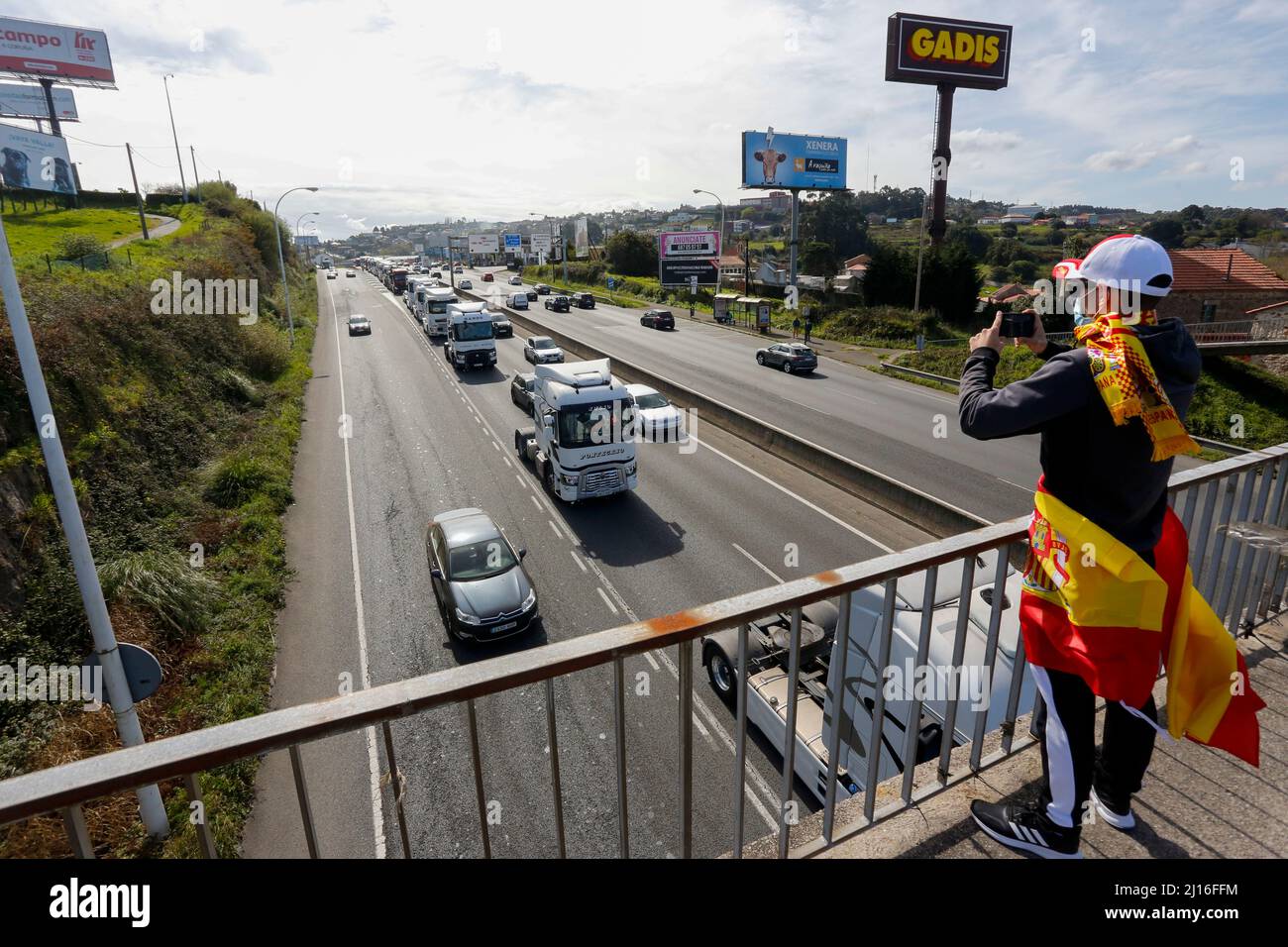 Ein Coruna-Spanien. Person mit dem Schal und der Nationalflagge von Spanien Aufnahme mit dem Handy die Passage des langsamen marsch von Lastwagen protestieren die Stockfoto