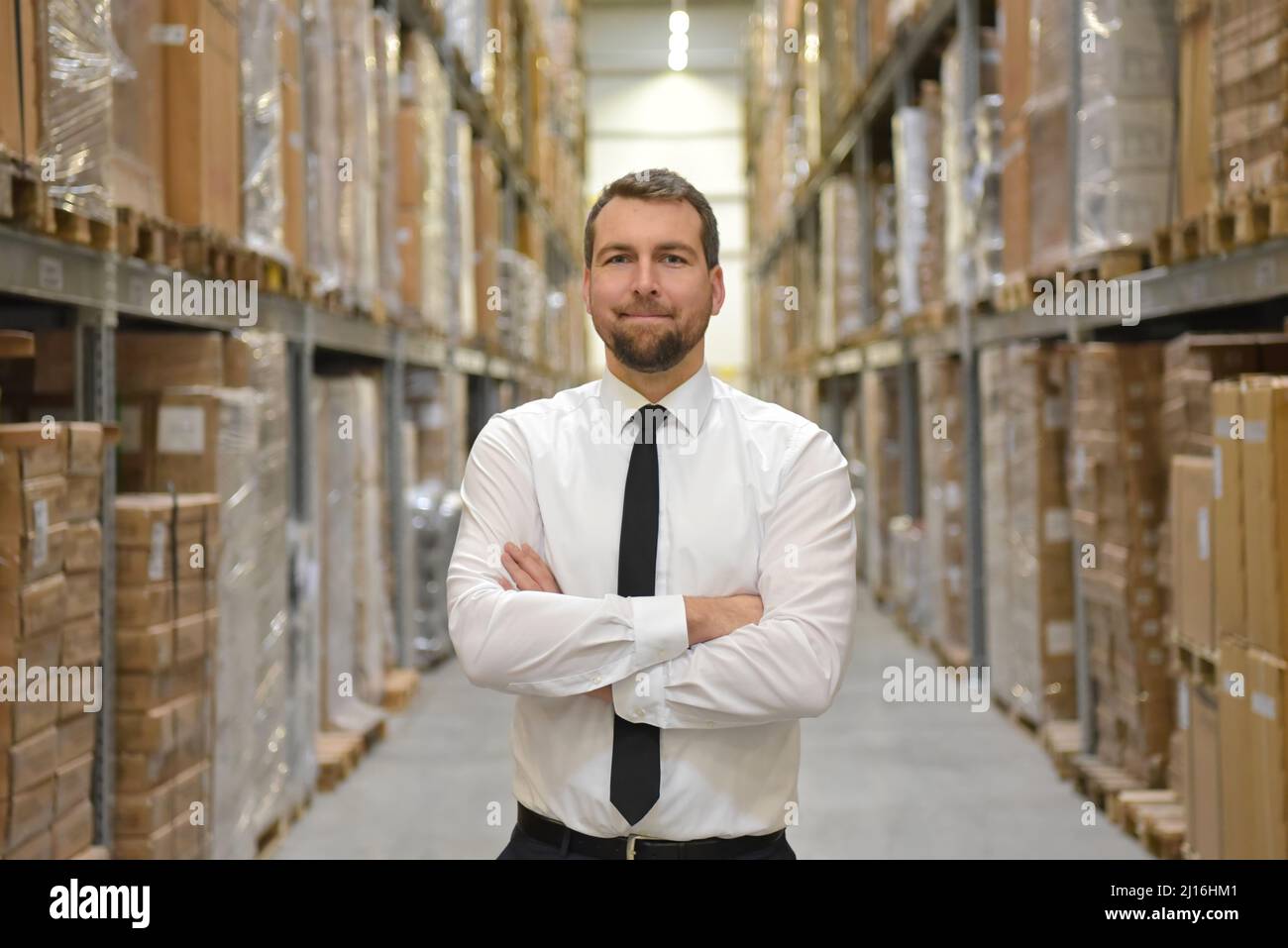 Portrait freundlicher Geschäftsmann/Manager im Anzug, der im Lager eines Unternehmens arbeitet Stockfoto