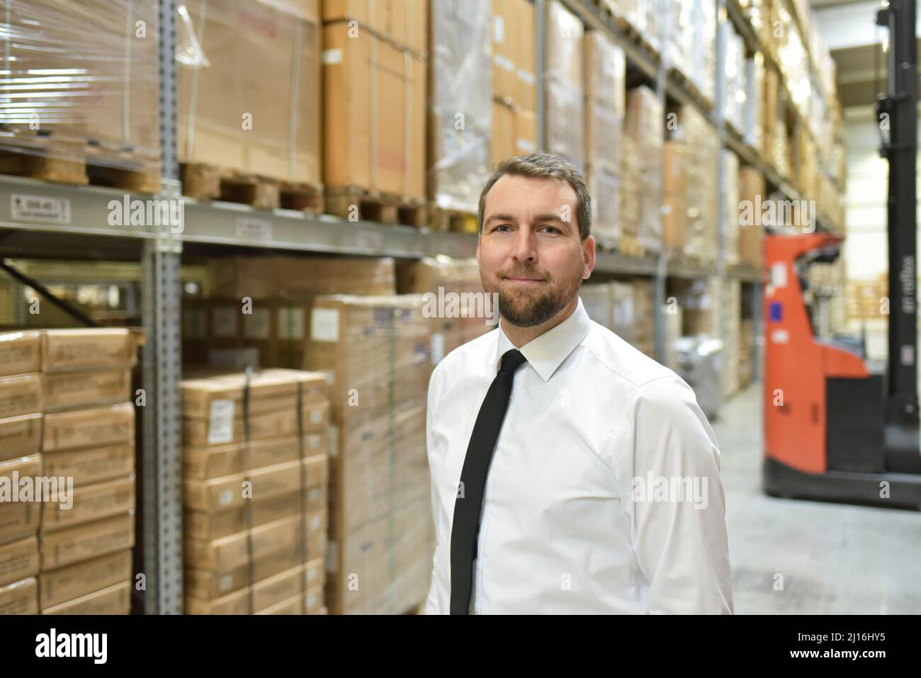 Portrait freundlicher Geschäftsmann/Manager im Anzug, der im Lager eines Unternehmens arbeitet Stockfoto