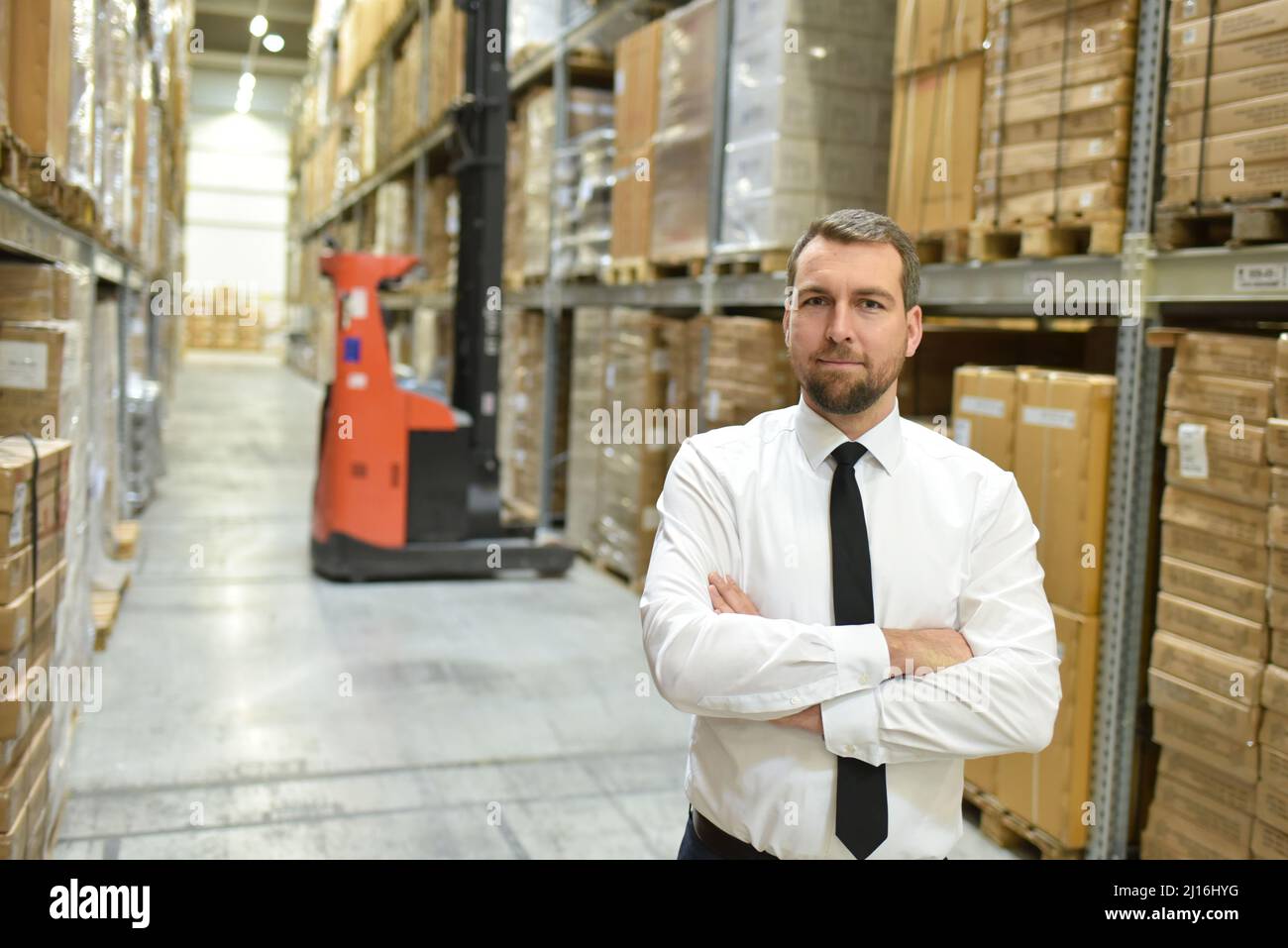 Portrait freundlicher Geschäftsmann/Manager im Anzug, der im Lager eines Unternehmens arbeitet Stockfoto