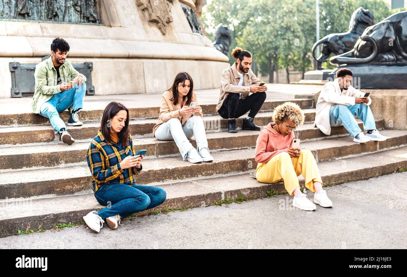 Gelangweilte Studenten Gruppe mit Handy sitzen auf dem Universitätshochschulhof - Junge Freunde süchtig nach Smartphone-Geräten - Technologie-Konzept w Stockfoto