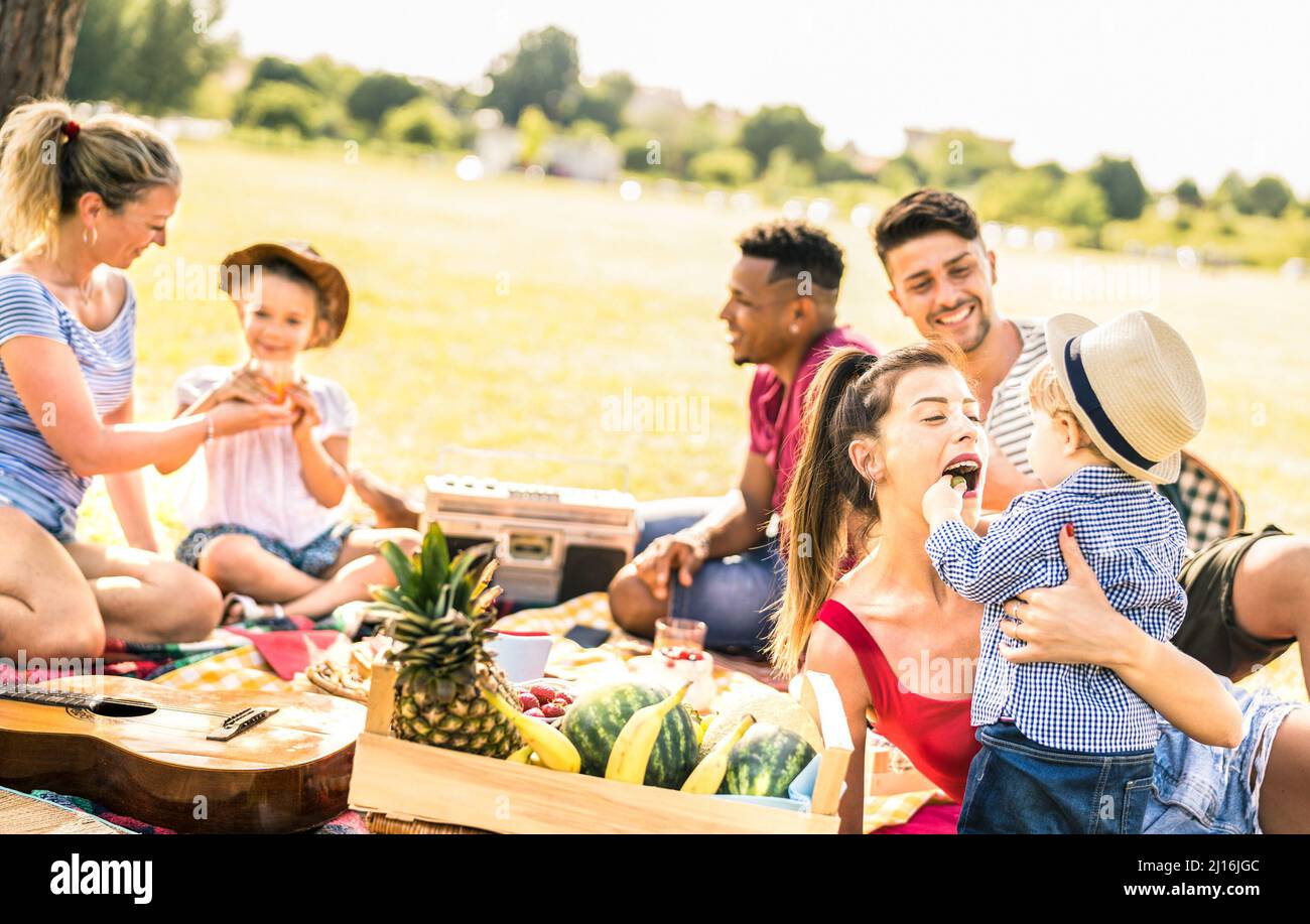 Glückliche multirassische Familien, die Spaß mit Kindern auf Picknick-Grillparty haben - multikulturelles Glück auf Freude und Liebe Konzept mit gemischten Rennen Menschen spielen Stockfoto