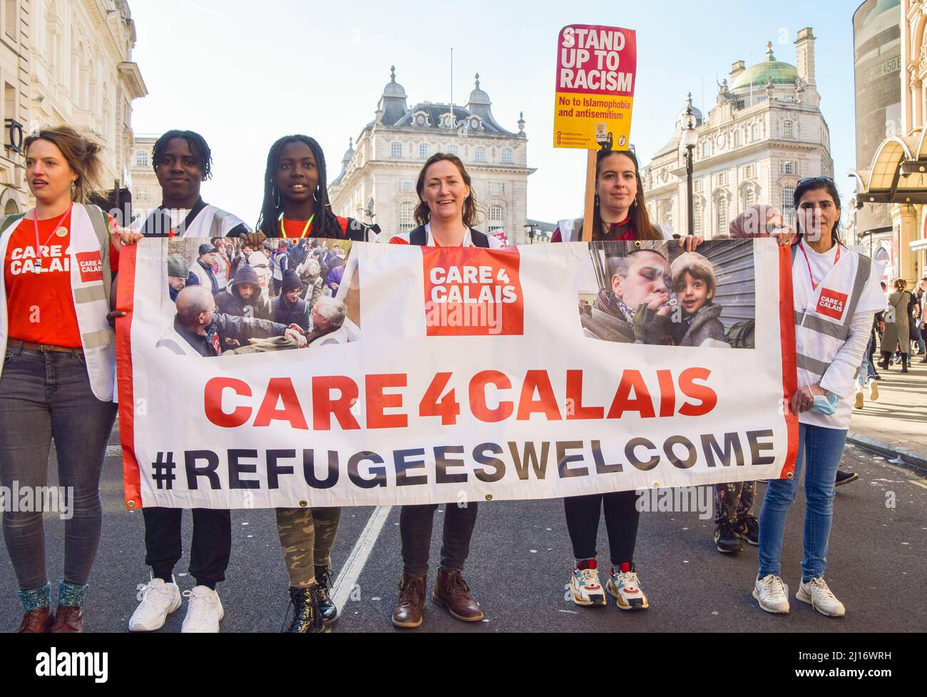 London, Großbritannien, 19.. März 2022. Demonstranten halten im Piccadilly Circus ein Transparent mit dem Titel „Care for Calais“. Tausende von Menschen marschierten durch Central London, um gegen Rassismus und Flüchtlinge zu protestieren. Stockfoto