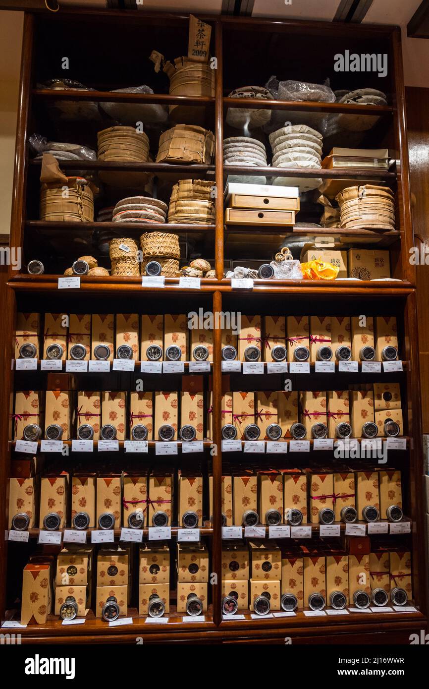 Schönes Holzregal mit Pu Erh Kuchen und viele Arten von verschiedenen verpackten Ursprungs-Tees. Lock Cha Tea House, Hongkong, China. Vertikale Aufnahme. Stockfoto