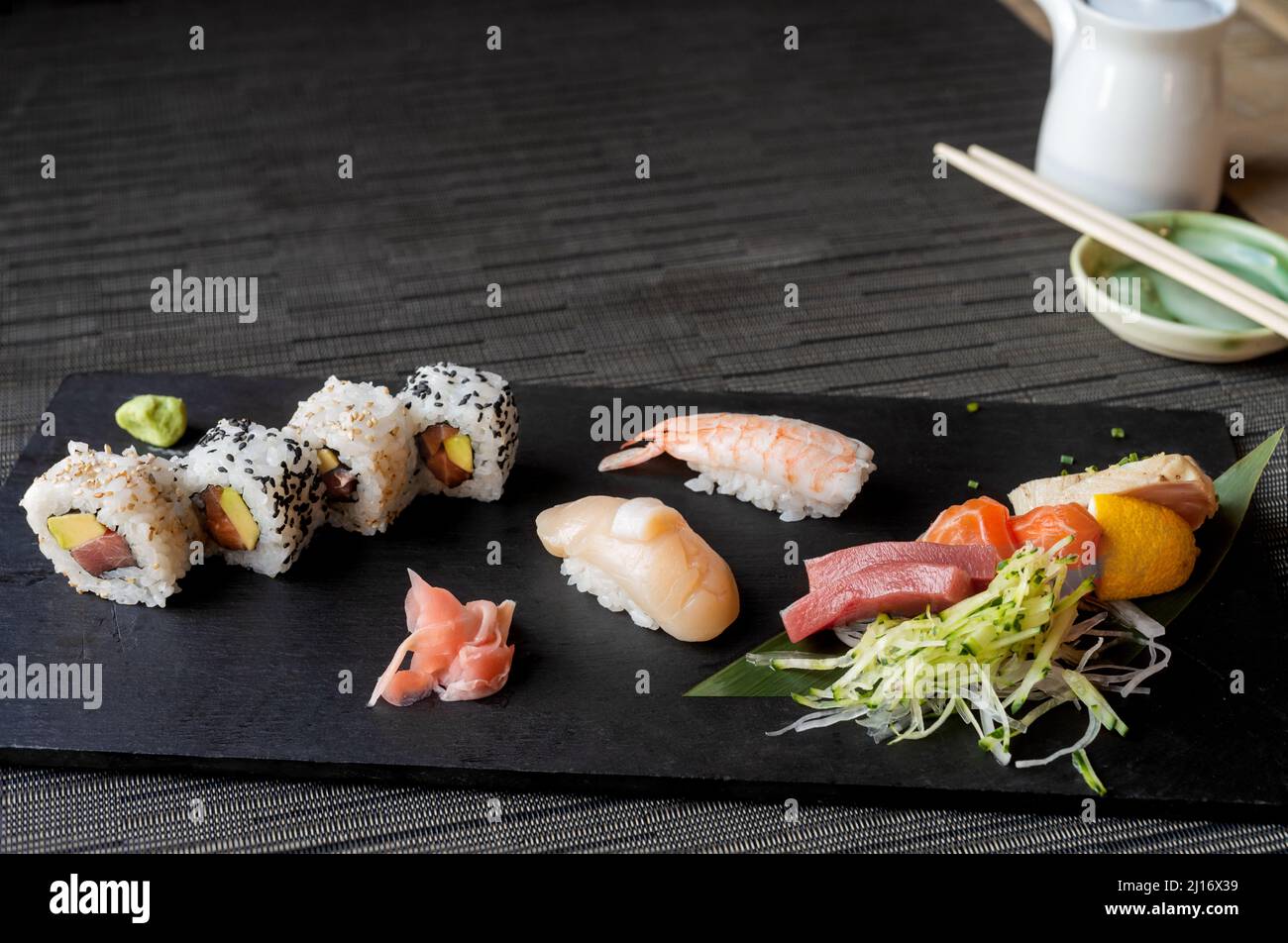 Tisch aus schwarzem Stein mit Sushi-Sorten auf schwarzer Tischdecke mit Platz zum Kopieren Stockfoto