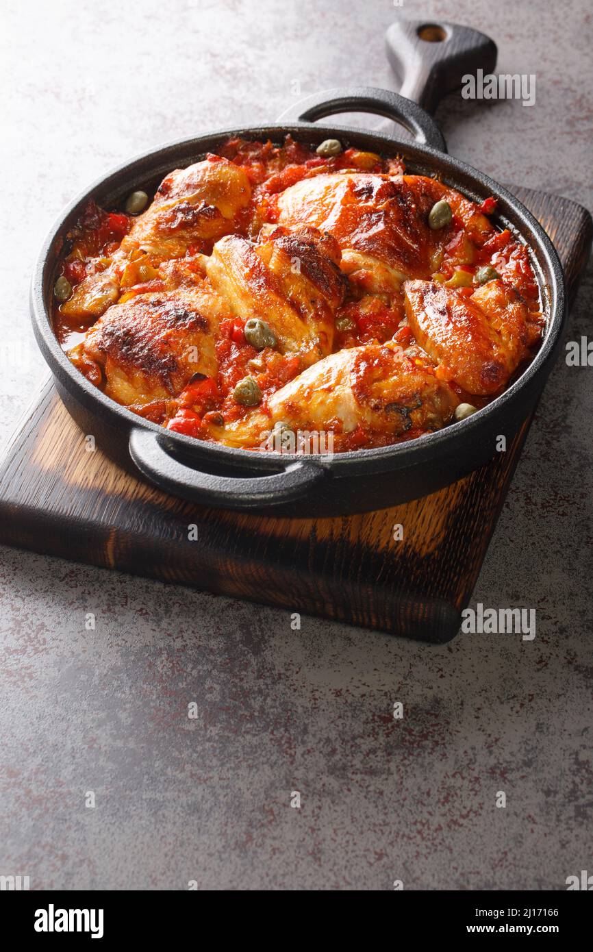 Mediterranes Huhn mit Tomaten, Paprika, Zwiebeln und Knoblauch in einer Pfanne auf dem Tisch gebacken. Vertikal Stockfoto