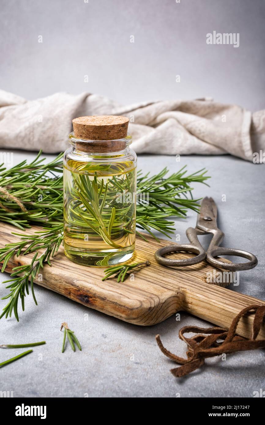 Glas Olivenöl mit Küchenkräutern grünem Thymian für gesunde Ernährung auf grauem Betongrund Stockfoto