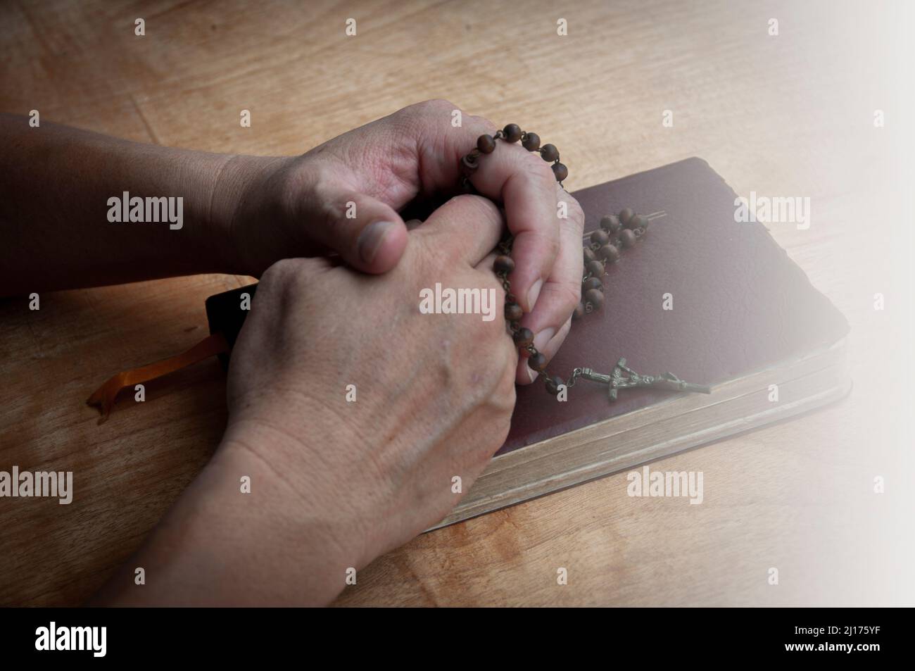 Hand hält Rosenkranz auf einer Heiligen Bibel beten. Christentum und Gebetskonzept. Stockfoto