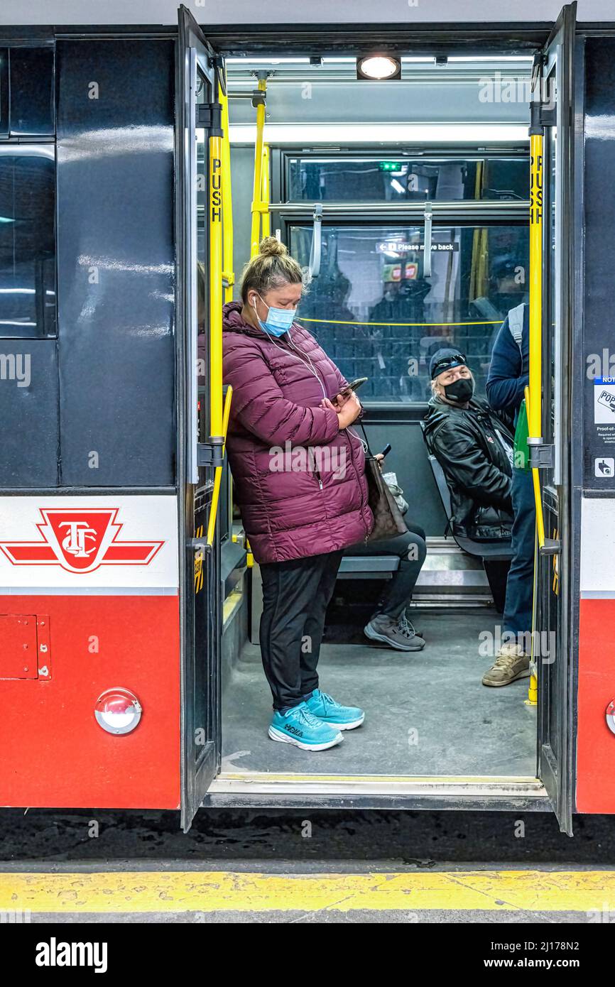 Eine Frau mit einer Gesichtsmaske, die in der offenen Tür eines TTC-Busses (Toronto Transit Commission) in der U-Bahn-Station York Mills steht. Stockfoto