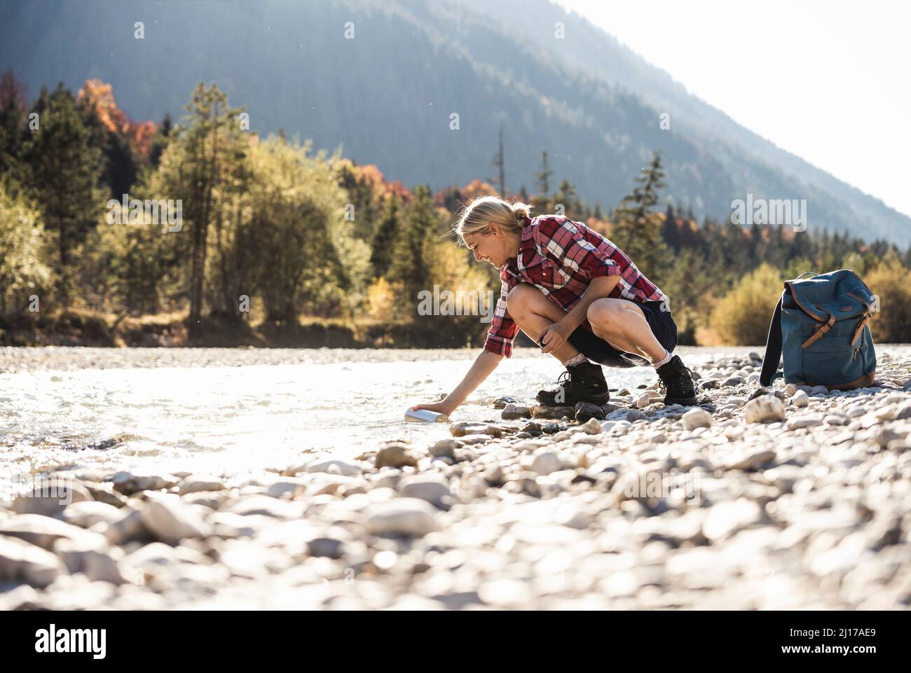 Österreich, Alpen, Frau auf einer Wanderung in einer Pause an einem Bach Stockfoto