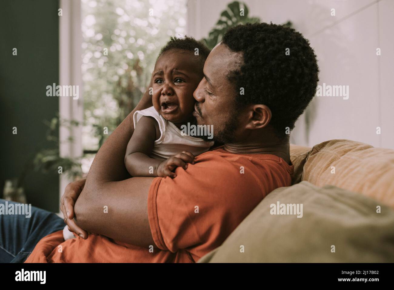 Vater beruhigt Baby Junge weinen im Wohnzimmer Stockfoto