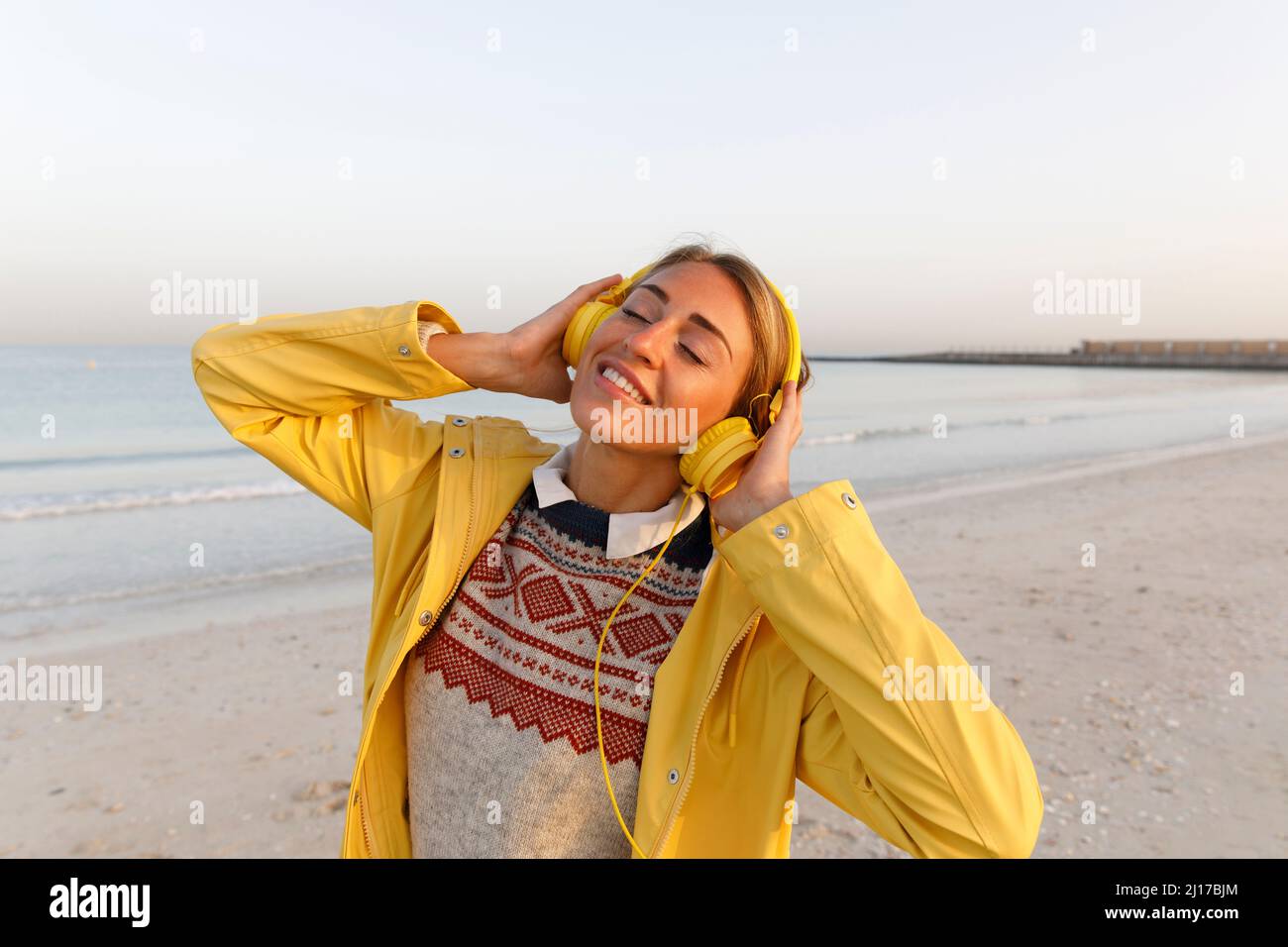 Glückliche Frau, die am Strand Musik genießt Stockfoto