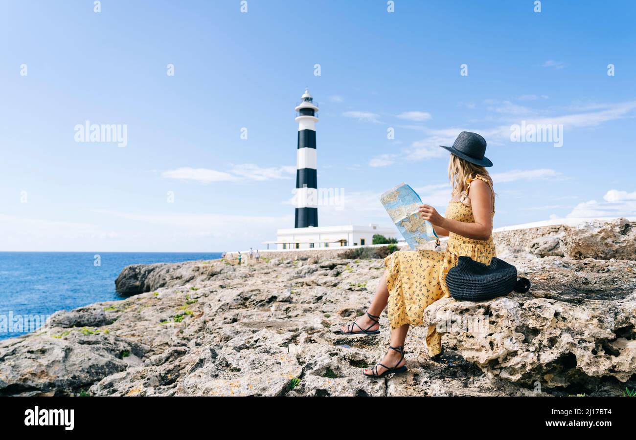 Tourist mit Karte auf Felsen am Leuchtturm von Artrutx in Menorca, Spanien Stockfoto