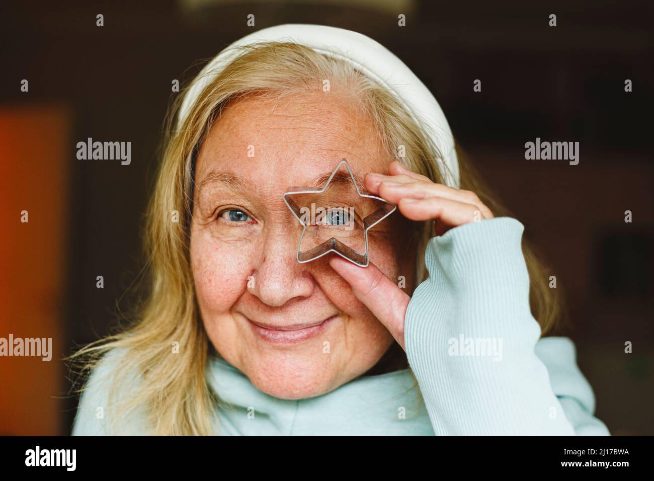 Ältere Frau schaut durch einen sternförmigen Ausstecher Stockfoto
