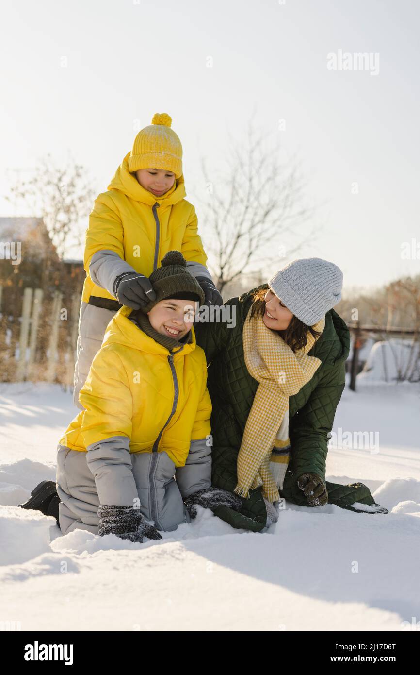 Fröhliche Jungen mit Mutter, die im verschneiten Garten genießt Stockfoto