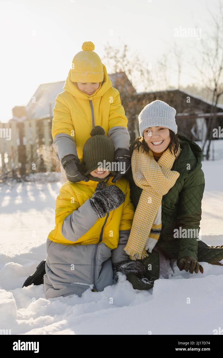 Verspielte Jungen mit Mutter im verschneiten Garten Stockfoto