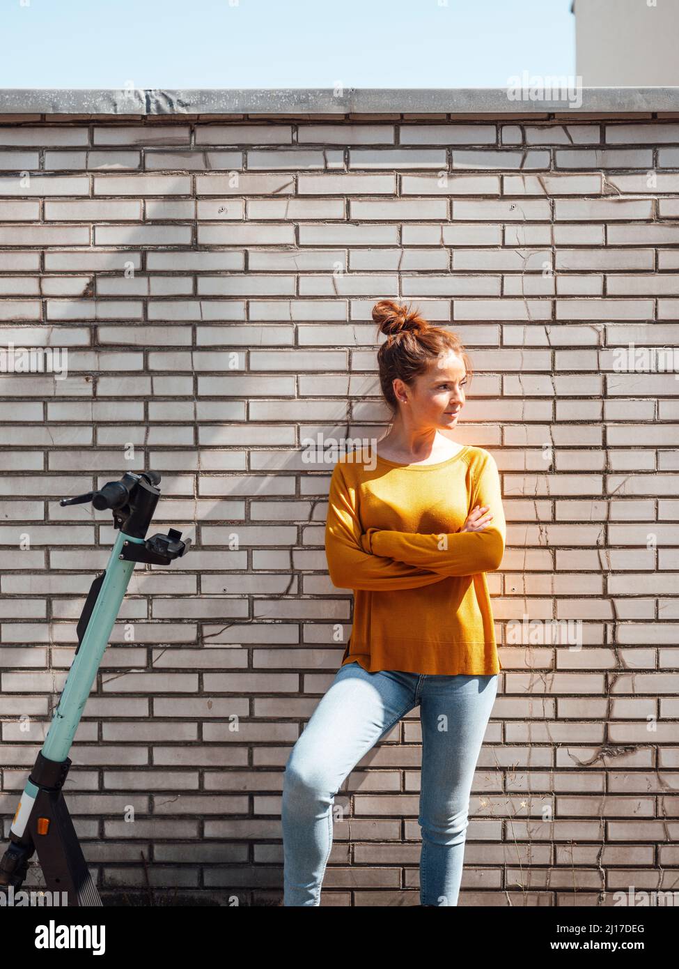 Junge Frau mit Armen von Elektro-Roller gekreuzt Stockfoto