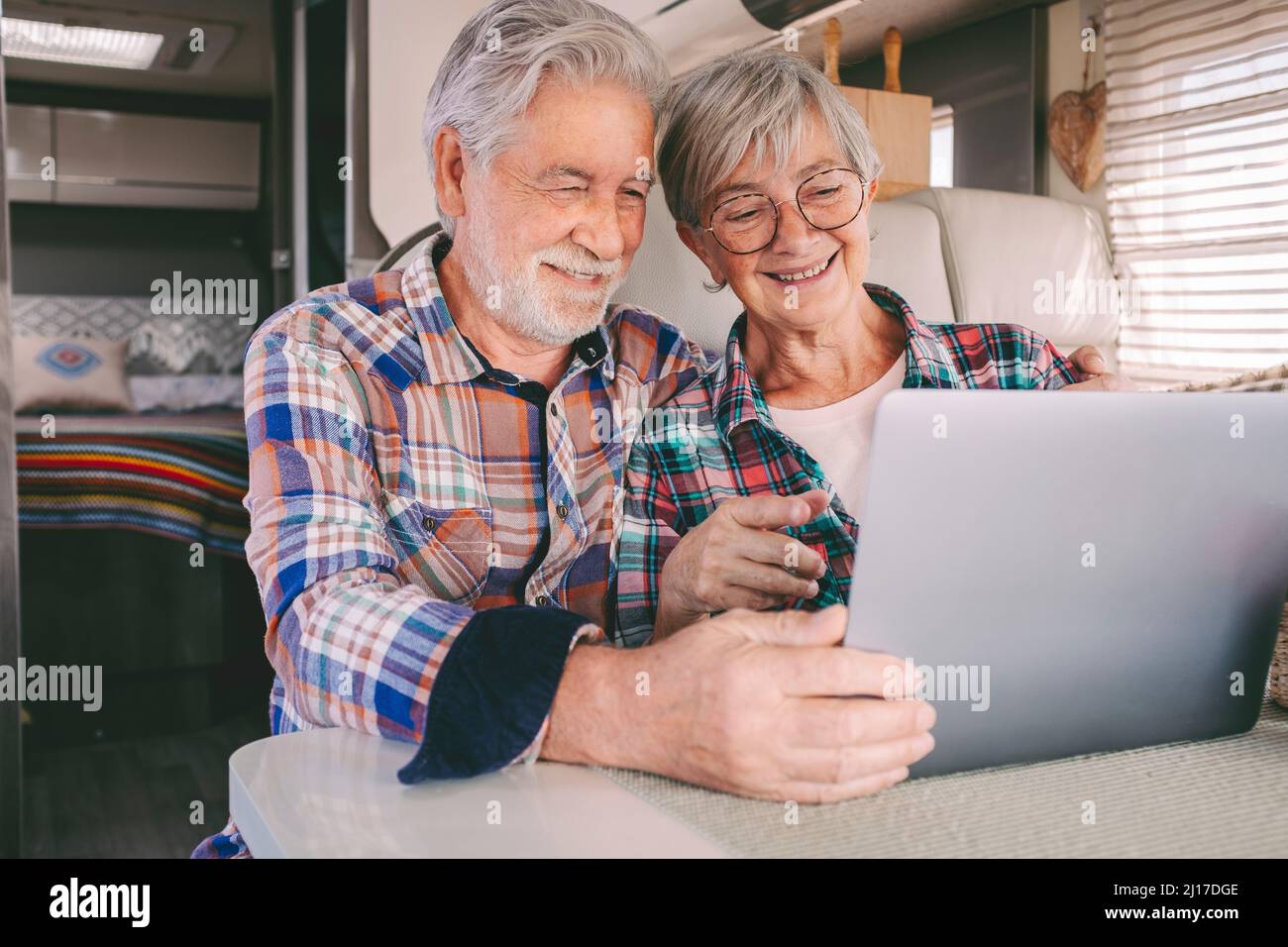 Glückliches Seniorenpaar mit Laptop im Wohnmobil Stockfoto