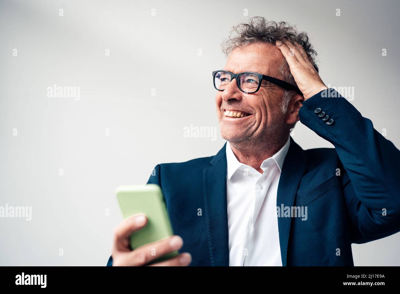 Fröhlicher Geschäftsmann mit Smartphone im Studio Stockfoto