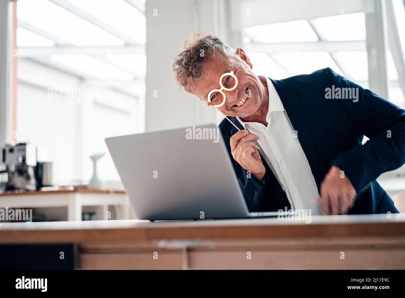 Fröhlicher Geschäftsmann mit Lorgnette auf Videoanruf über Laptop Stockfoto