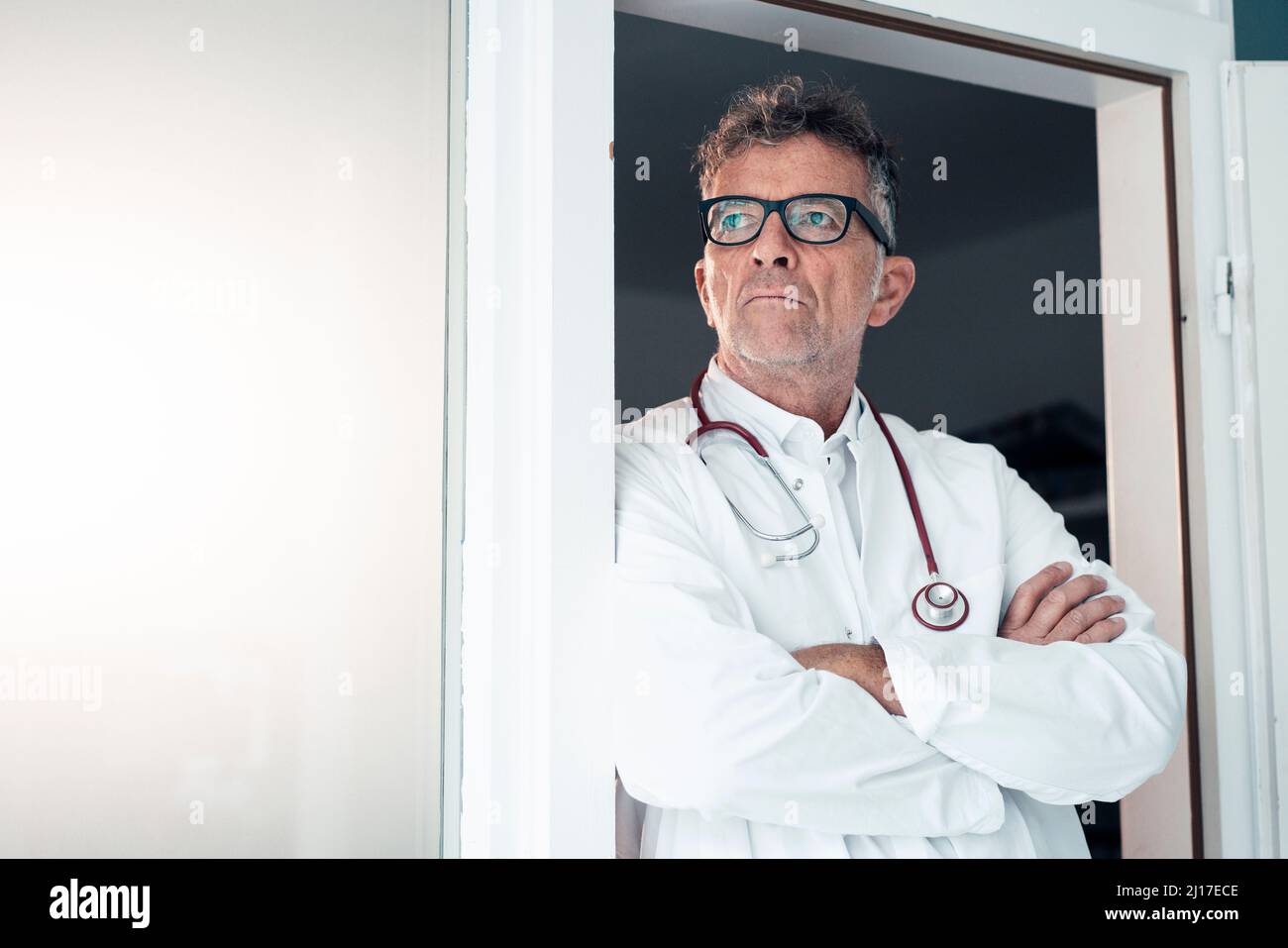 Hausarzt mit gekreuzten Armen in der Klinik Stockfoto