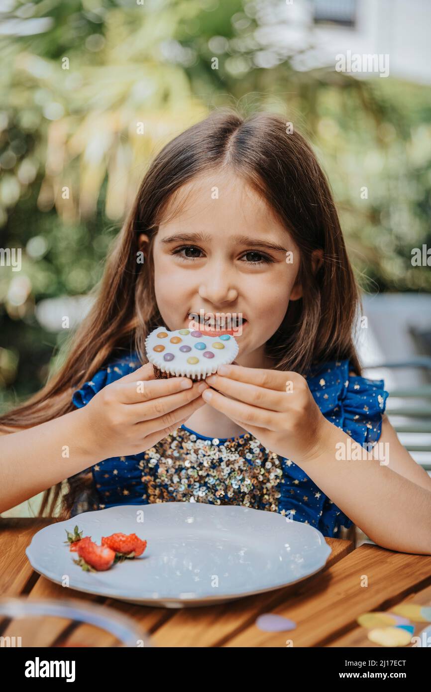 Lächelndes Mädchen mit Cupcake auf Geburtstagsfeier Stockfoto