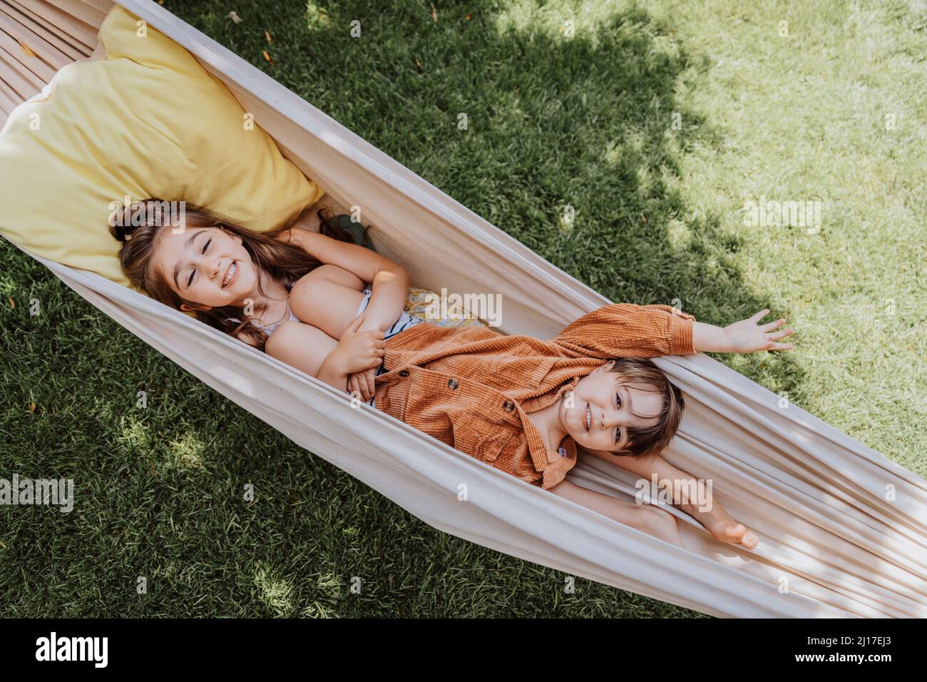 Lächelnde Schwester und Bruder liegen in der Hängematte auf dem Hinterhof Stockfoto