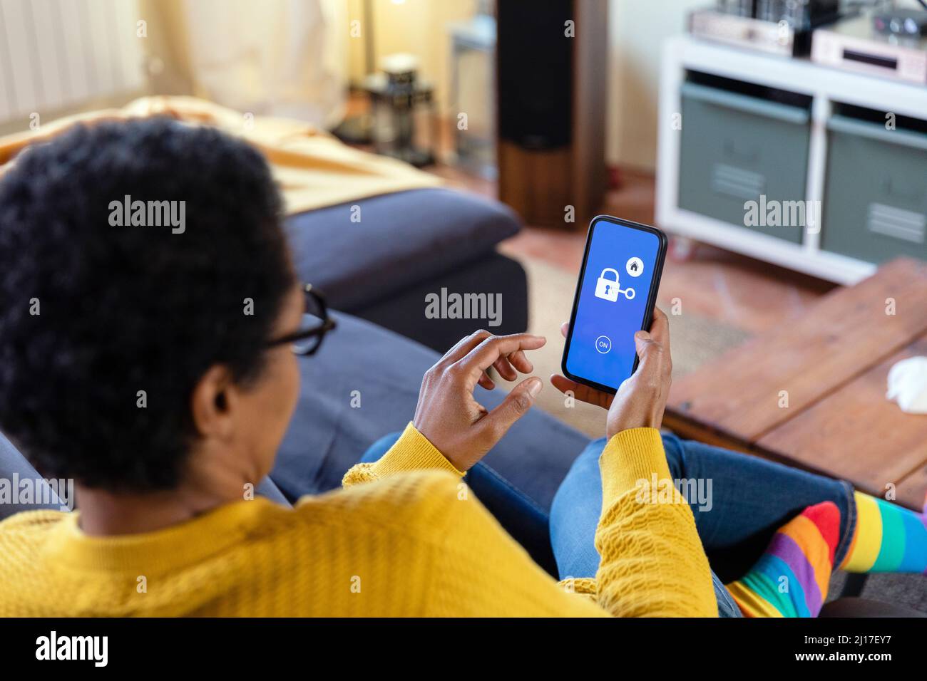 Frau, die die App auf dem Smartphone im Wohnzimmer verwendet Stockfoto