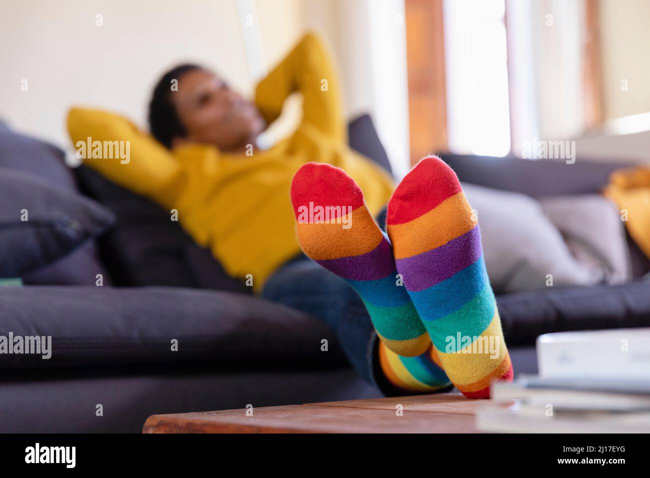 Frau trägt mehrfarbige Socken im Wohnzimmer Stockfoto