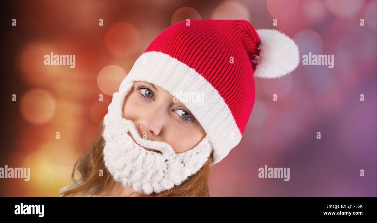Porträt einer kaukasischen Frau mit weihnachtsmann-Hut und Bart vor Lichtflecken im Hintergrund Stockfoto