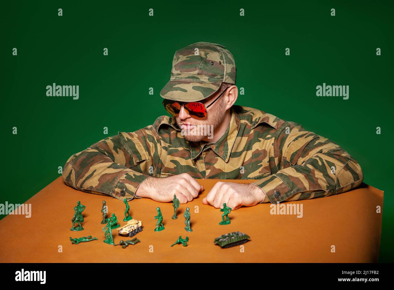 Militärsoldat mit Armeefiguren vor grünem Hintergrund Stockfoto