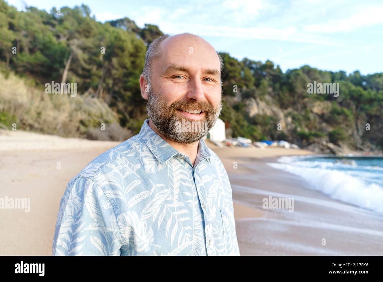 Lächelnder Mann mit Bart am Strand Stockfoto