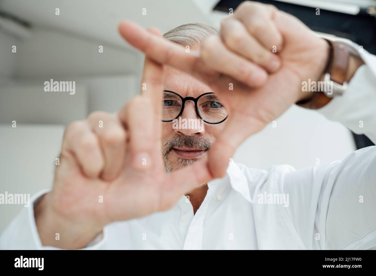 Geschäftsmann, der den Fingerrahmen am Arbeitsplatz gestikelt Stockfoto