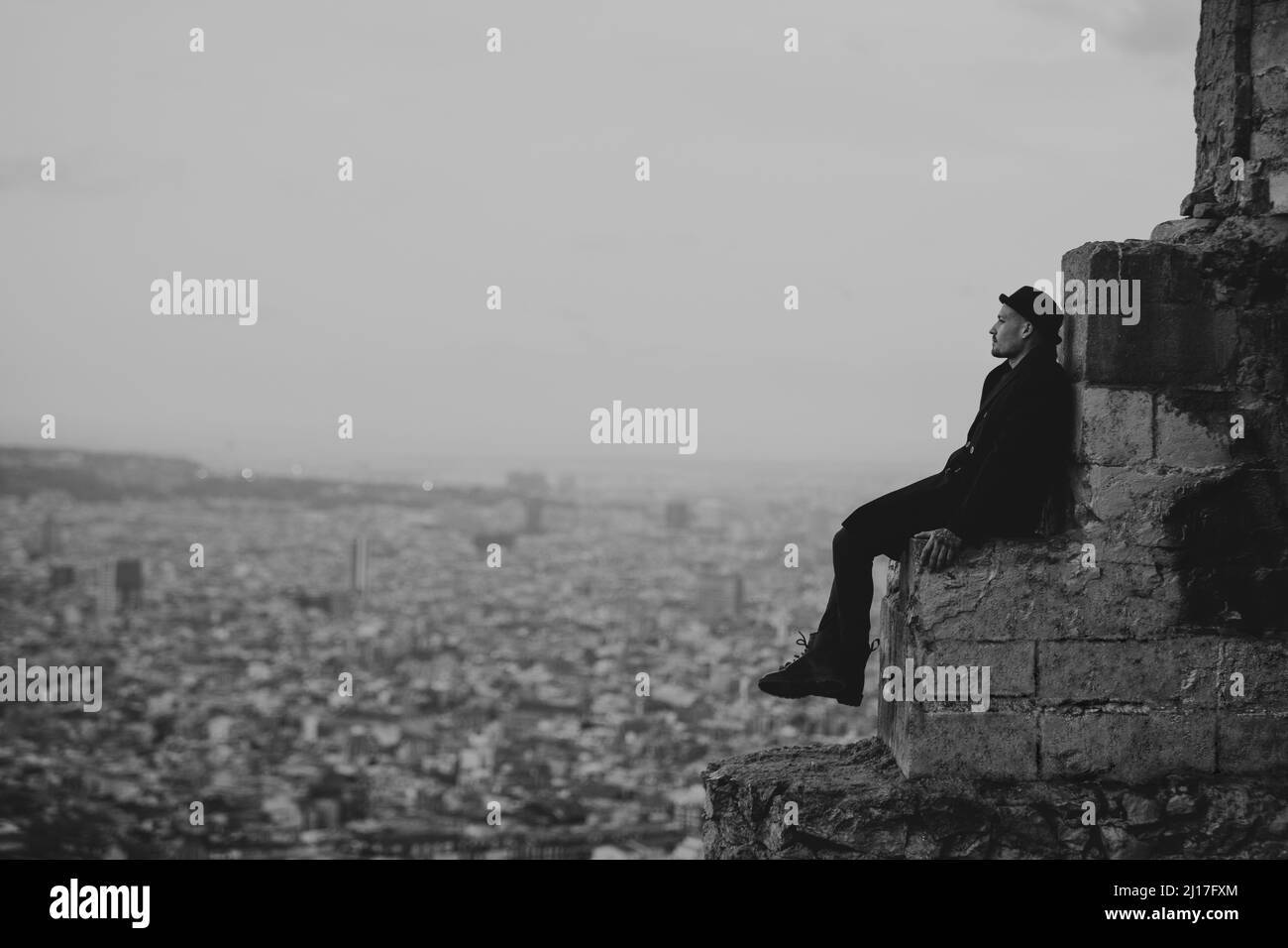 Kontemplativer Mann, der in der Stadt auf Felsen sitzt Stockfoto