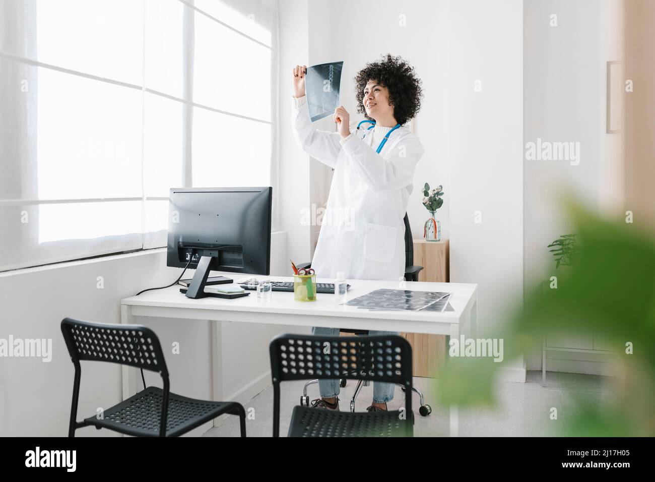 Arzt, der medizinische Röntgenaufnahmen untersucht und auf dem Schreibtisch im Krankenhaus steht Stockfoto