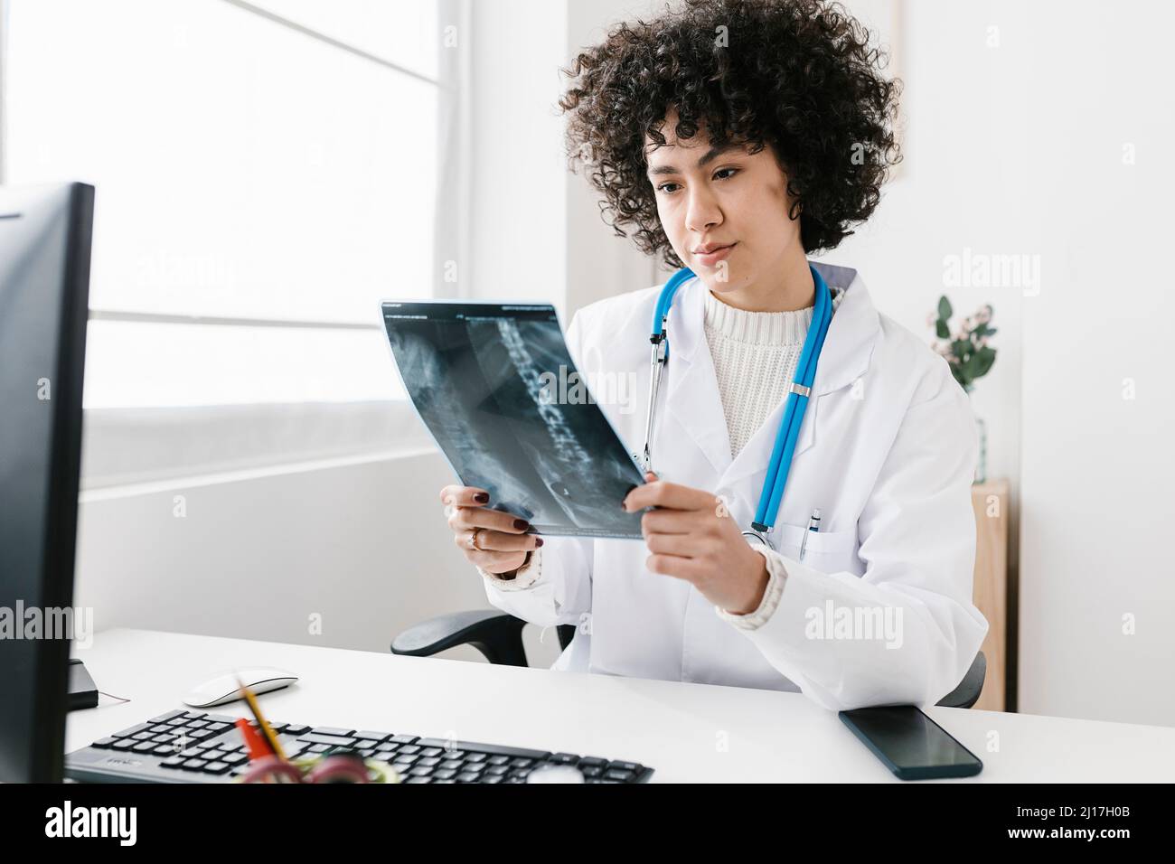 Arzt, der Röntgenbericht untersucht, sitzt in der medizinischen Klinik Stockfoto