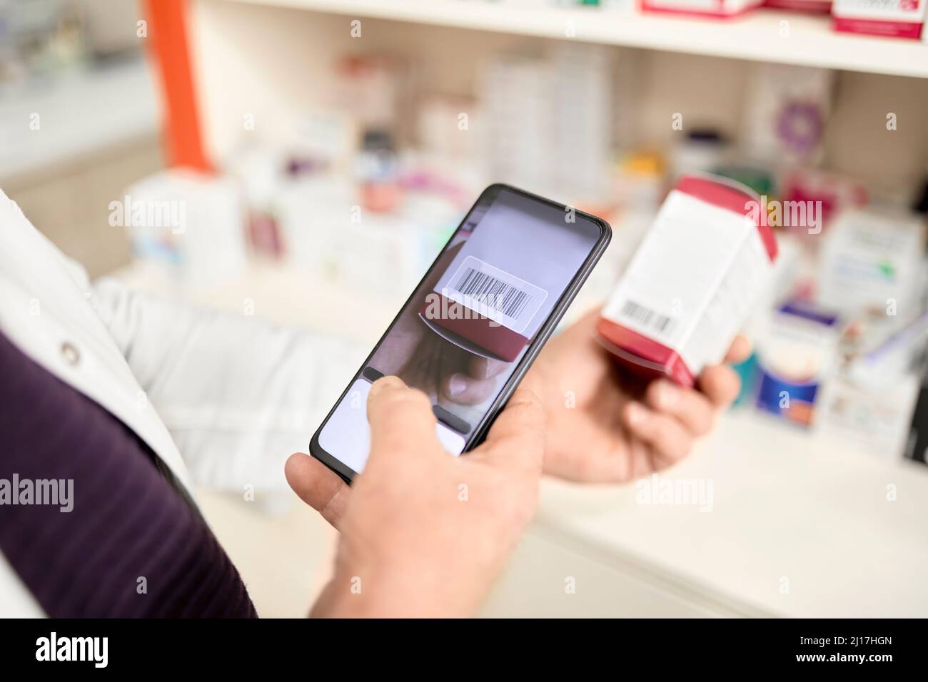 Apotheker scannt den Barcode der Medikamentenkiste über das Smartphone im Apothekengeschäft Stockfoto
