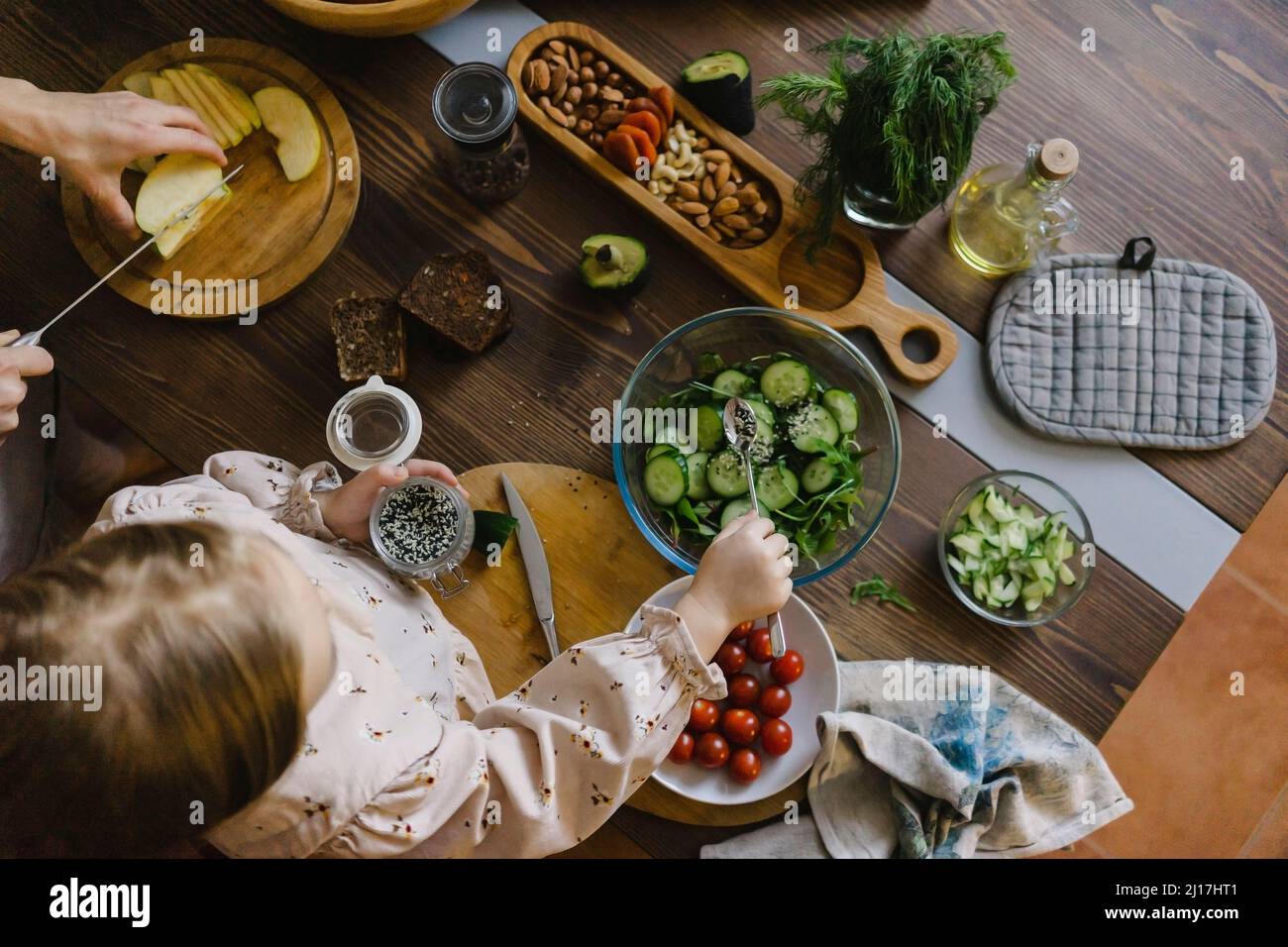 Mädchen macht Salat von Mutter schneiden Lebensmittel in der Küche zu Hause Stockfoto