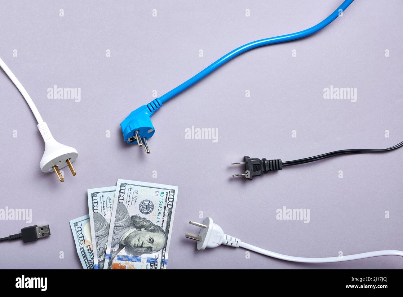 Konzeptionelles Bild über die hohen wirtschaftlichen Kosten von Strom und die Zunahme der Energiepreise: Stromkabel rund um die Dollar-Banknote. Stockfoto