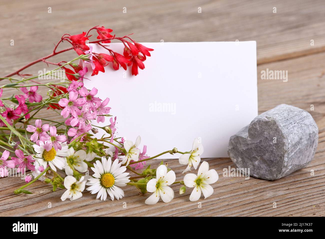 Herzförmiger Stein mit einem kleinen Blumenstrauß Stockfoto