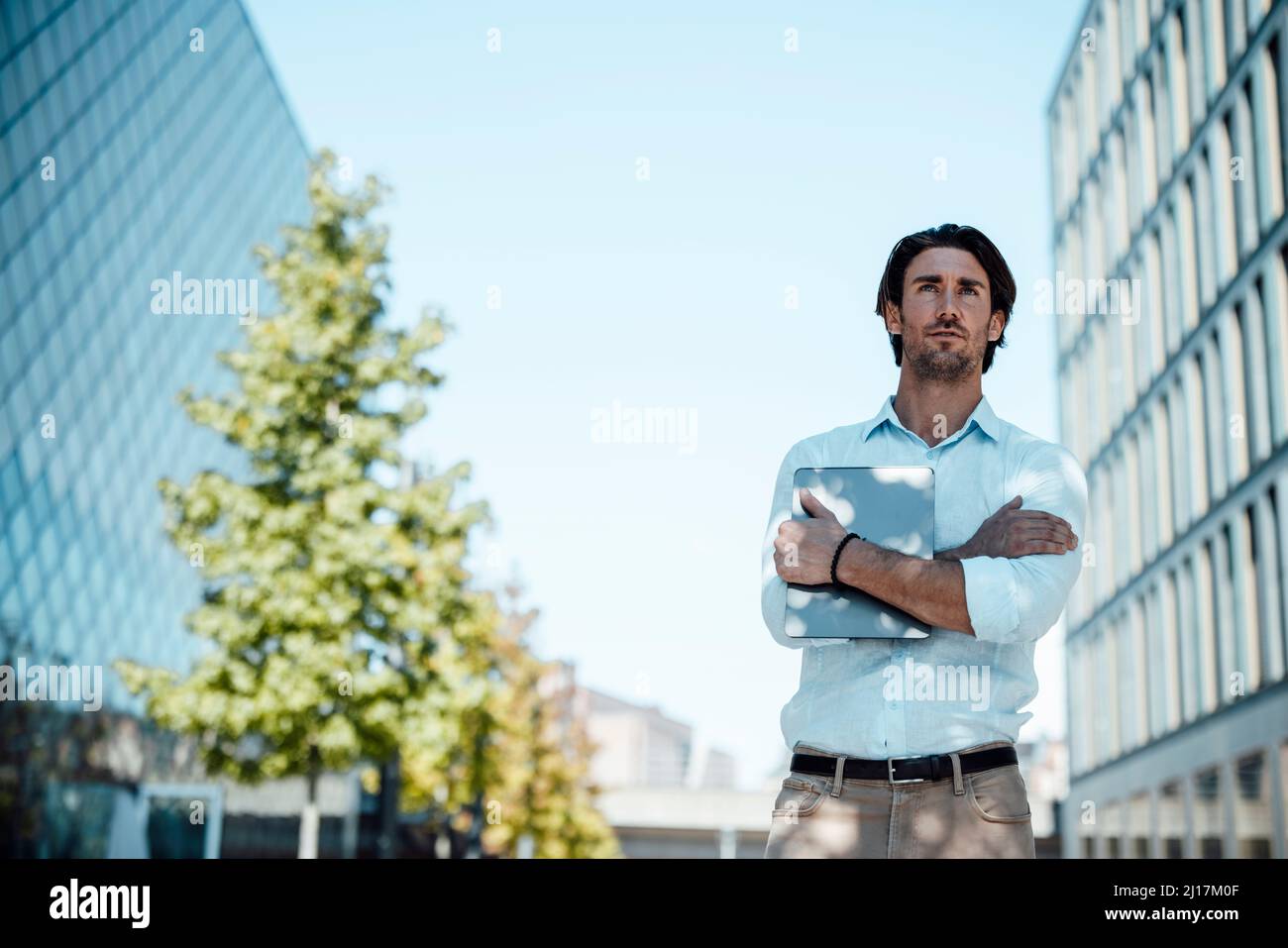 Geschäftsmann, der mit gekreuzten Armen im Büropark steht Stockfoto