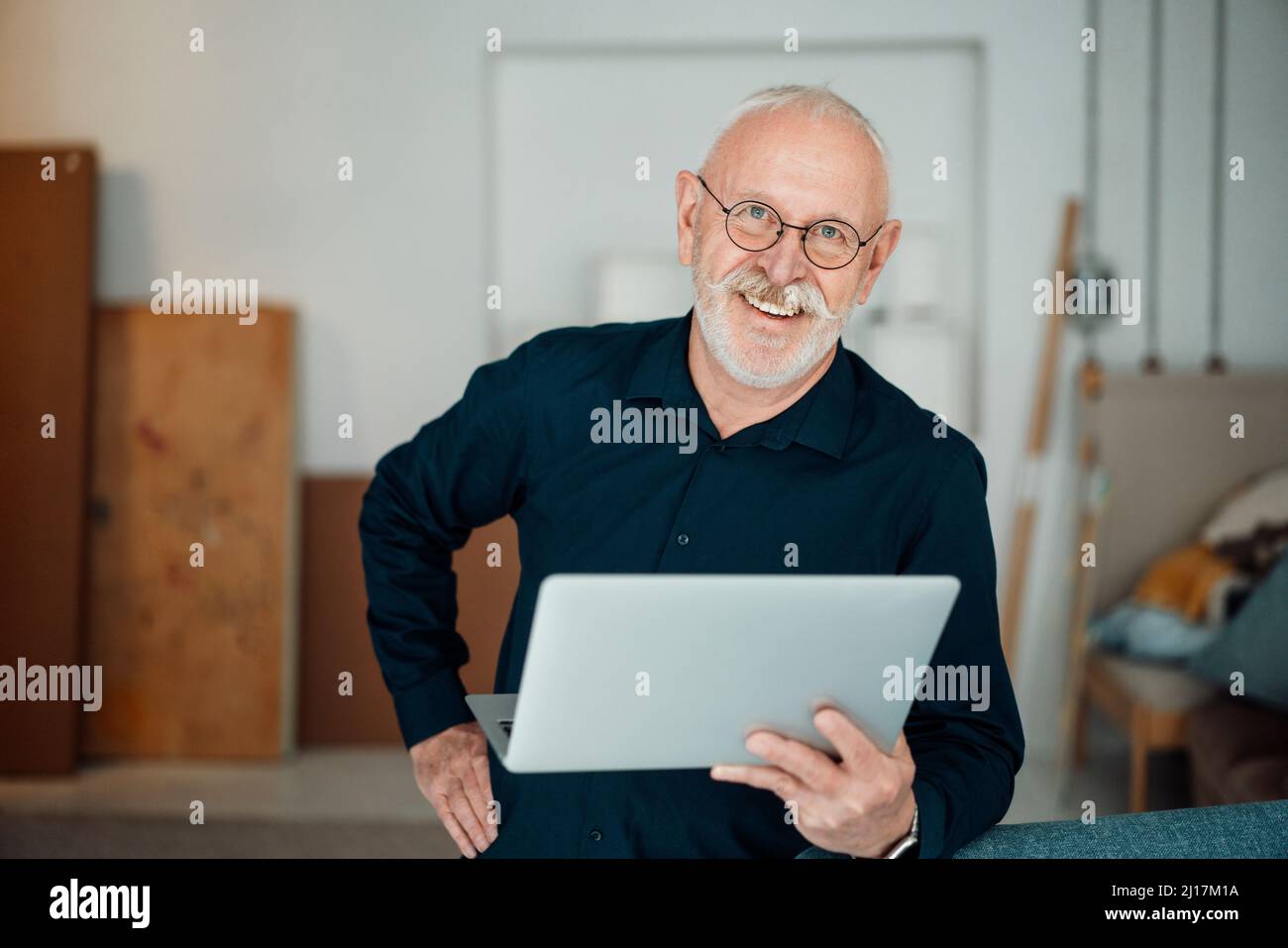 Glücklicher Mann mit Laptop im Büro Stockfoto